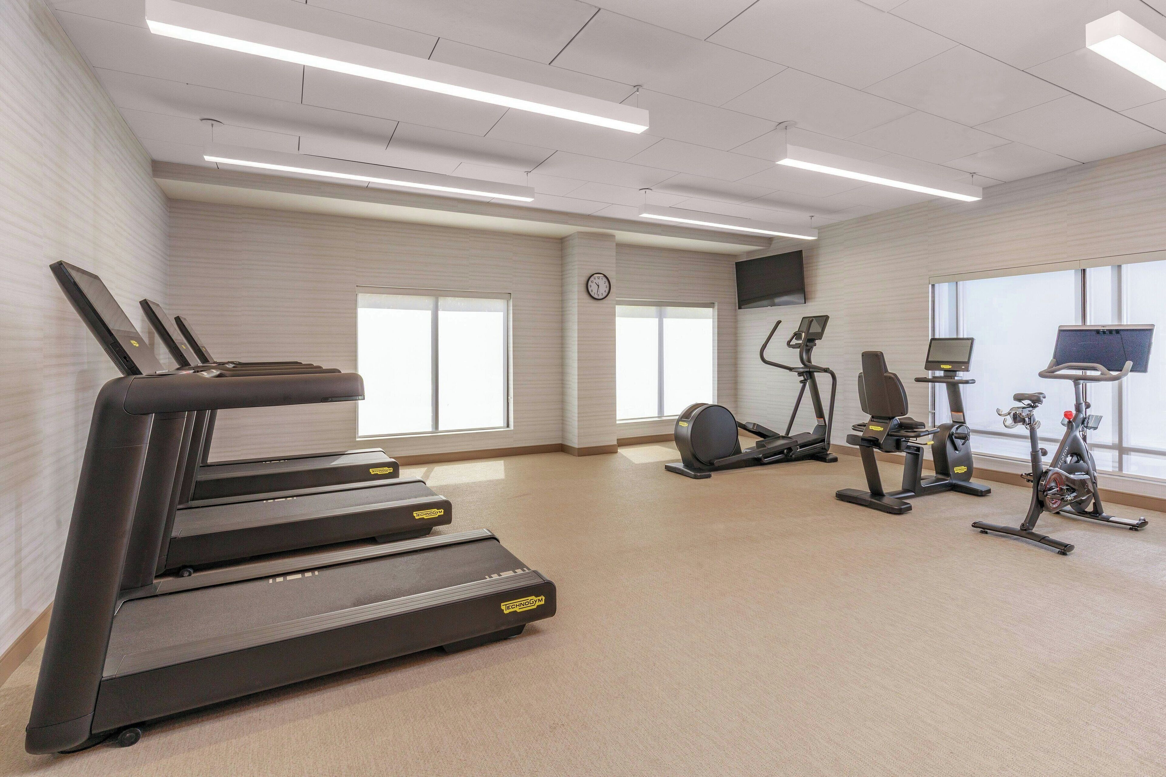 A fitness room with treadmills, stationary bikes, and an elliptical machine.