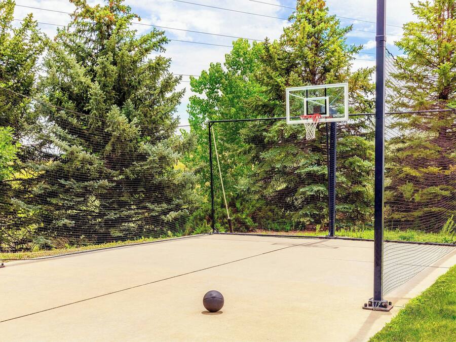 Una cancha de baloncesto al aire libre con aro, red y balón.