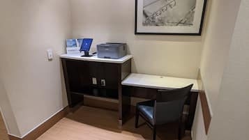 A small office space with a desk, chair, printer, and a framed artwork on the wall.