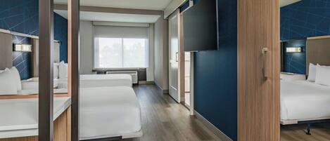 Habitación de hotel con dos camas, televisión y ventana.