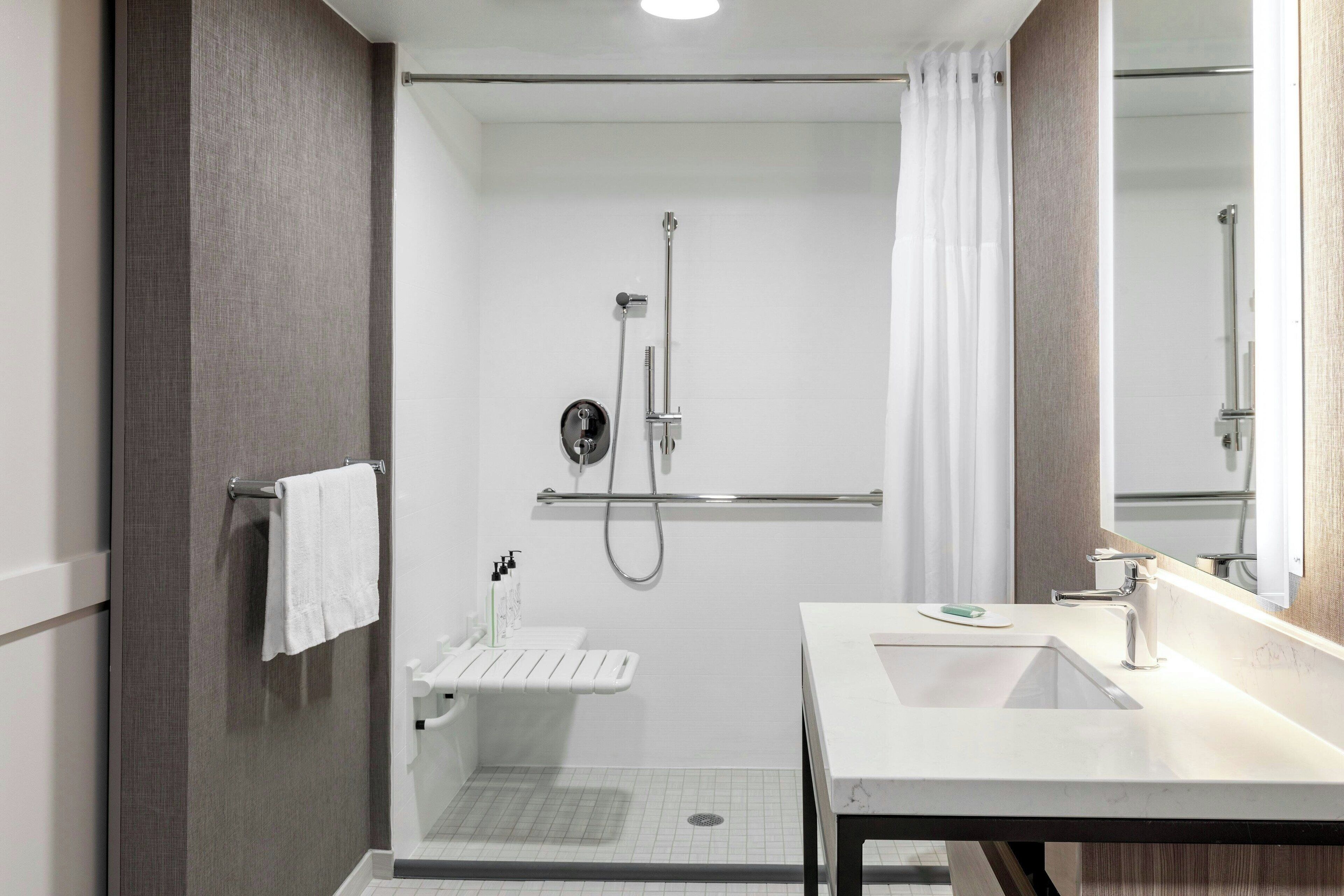 A modern bathroom with a walk-in shower, a vanity with a sink, and a mirror.