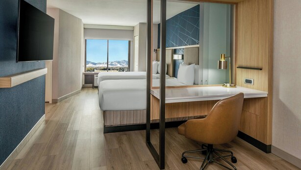 A modern hotel room with a large bed, a desk with a chair, a flat-screen TV, and a large window offering a mountain view. - Springhill Suites By Marriott Denver Westminster (Westminster)
