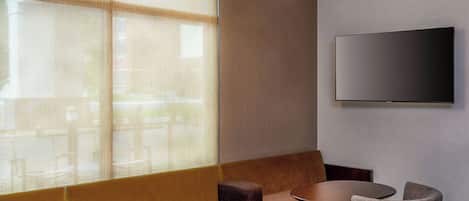 Un interior moderno con un sofá, dos mesas redondas y un televisor de pantalla plana montado en la pared.