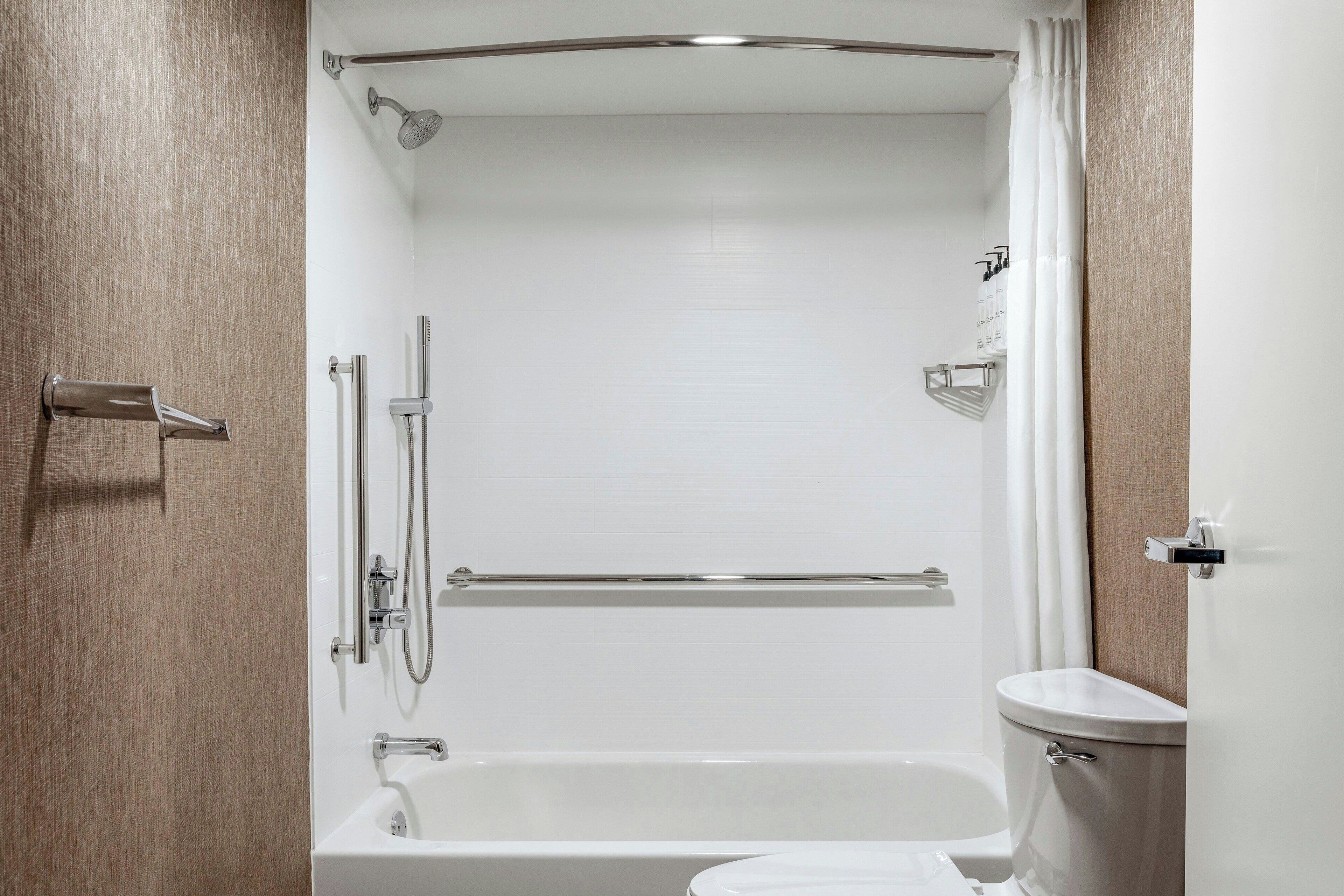 A modern bathroom with a bathtub, shower, and toilet.