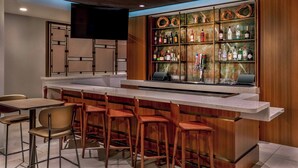 A modern bar area with a long counter, multiple stools, and a variety of liquor bottles. - Springhill Suites By Marriott Denver Westminster (Westminster)