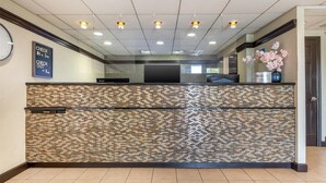A reception area with a tiled wall, a clock, and a vase of flowers.