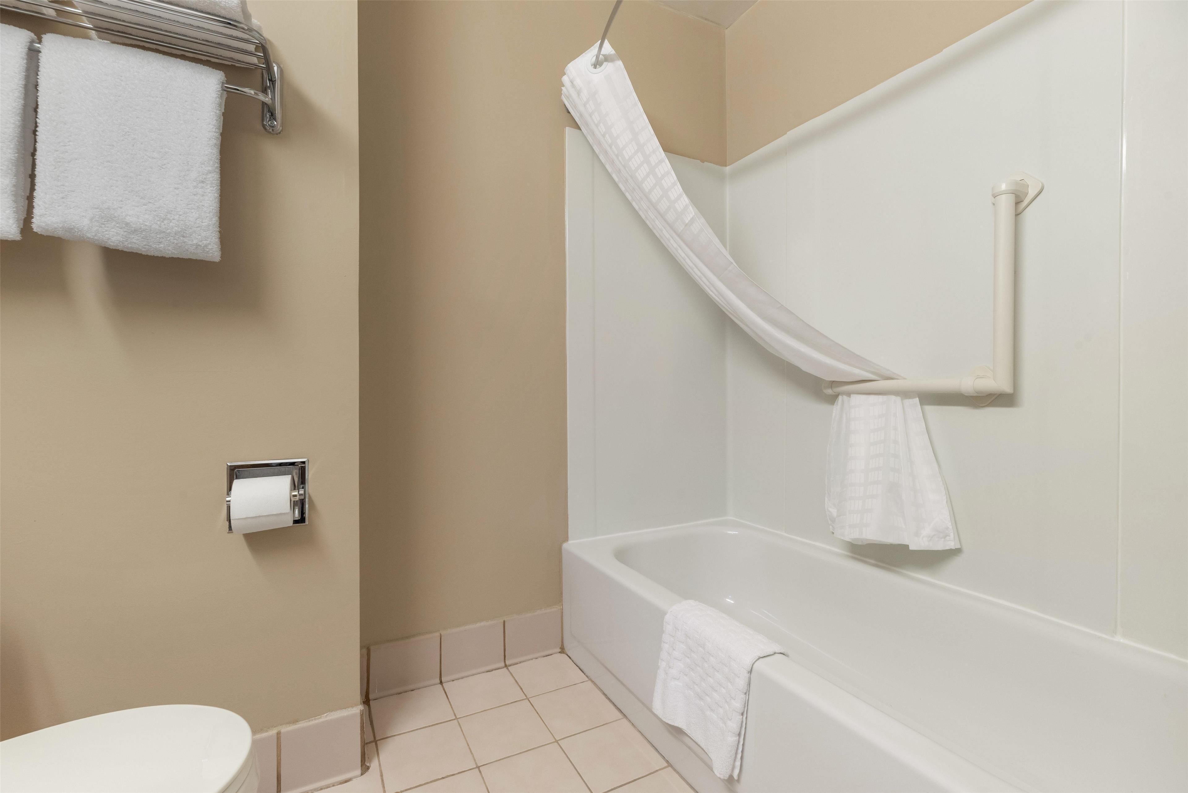 A bathroom with a bathtub, a toilet, and a towel rack with towels.