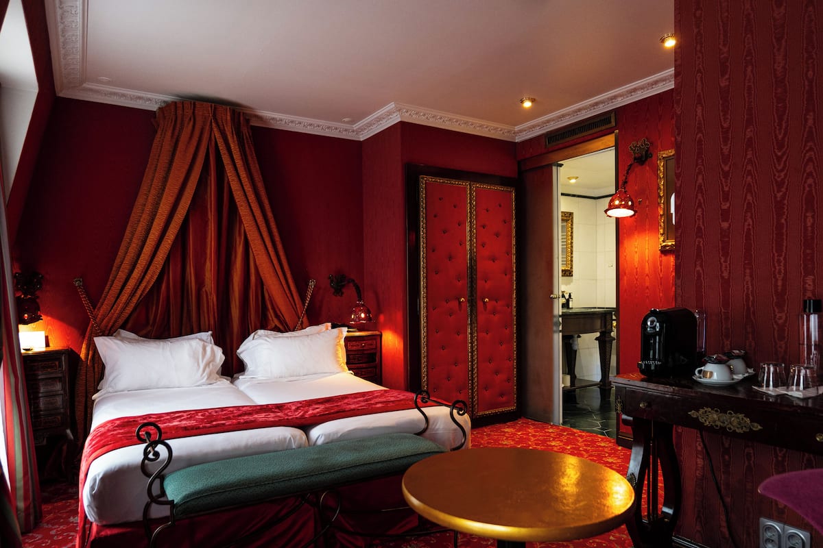 A hotel room with a large bed, a small round table, and a mirror.