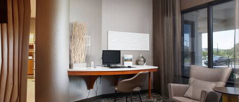 Habitación de hotel con escritorio, dos sillas, un ventanal y vistas al exterior.