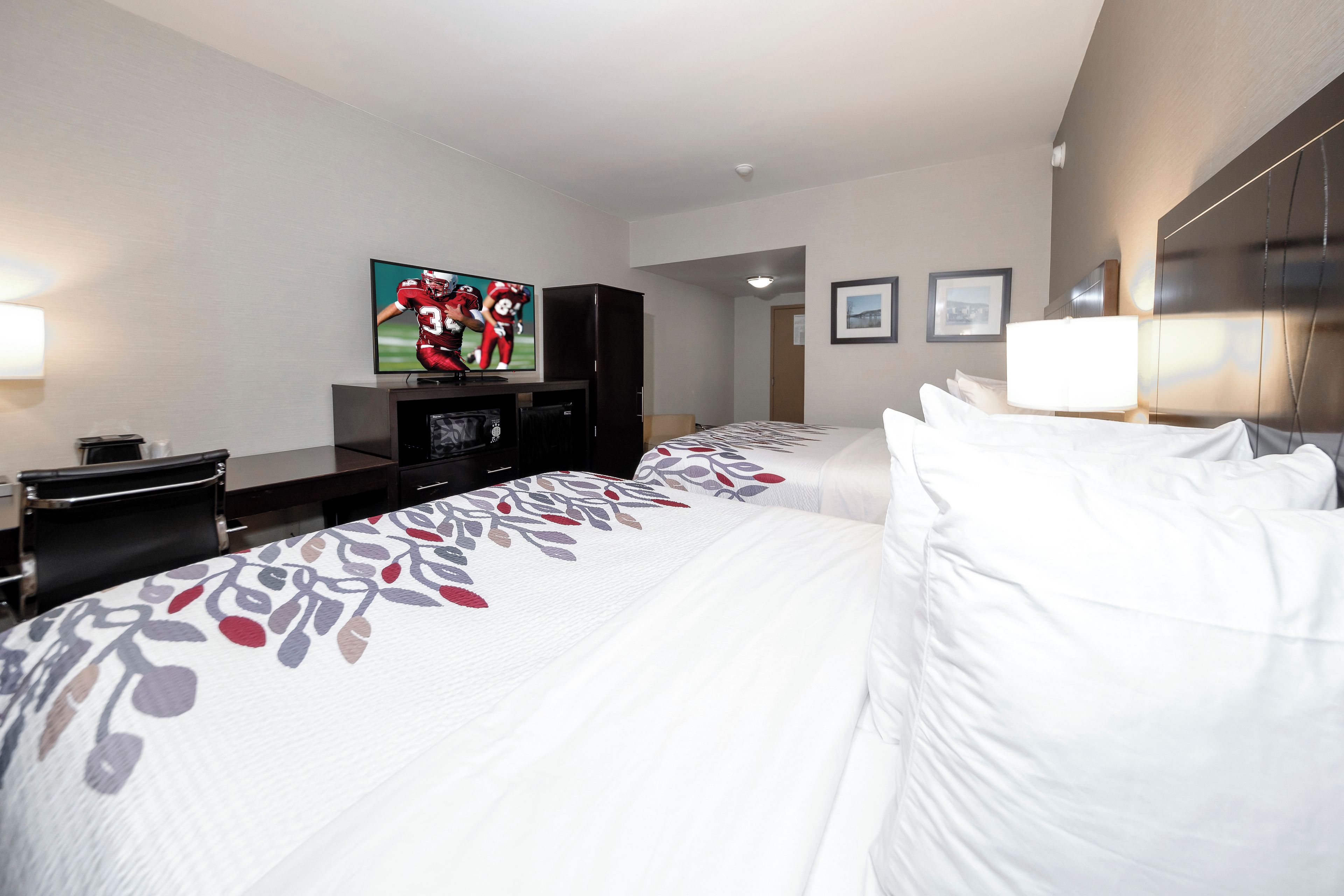 Una habitación de hotel con dos camas, un televisor, un escritorio y una puerta.