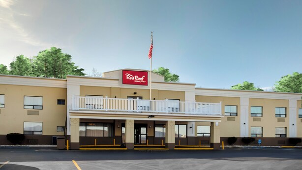 A Red Roof Inn & Suites building with a two-story structure, a balcony, and an American flag. - Red Roof Inn & Suites Newburgh – Stewart Airport/ West Point (New Windsor)