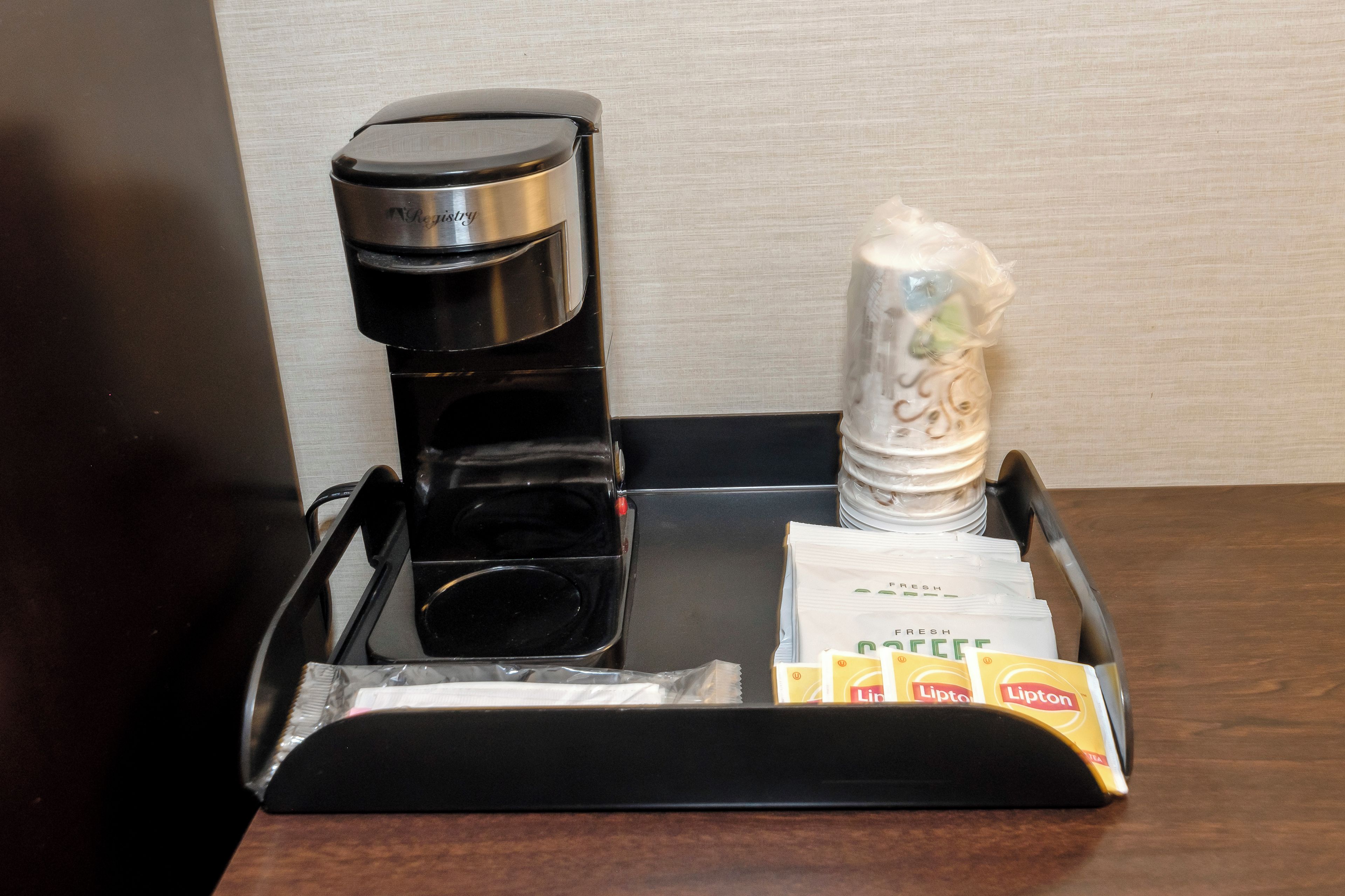 A coffee maker, salt and pepper shakers, and Lipton tea packets on a tray.