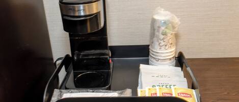 A coffee maker, salt and pepper shakers, and Lipton tea packets on a tray.