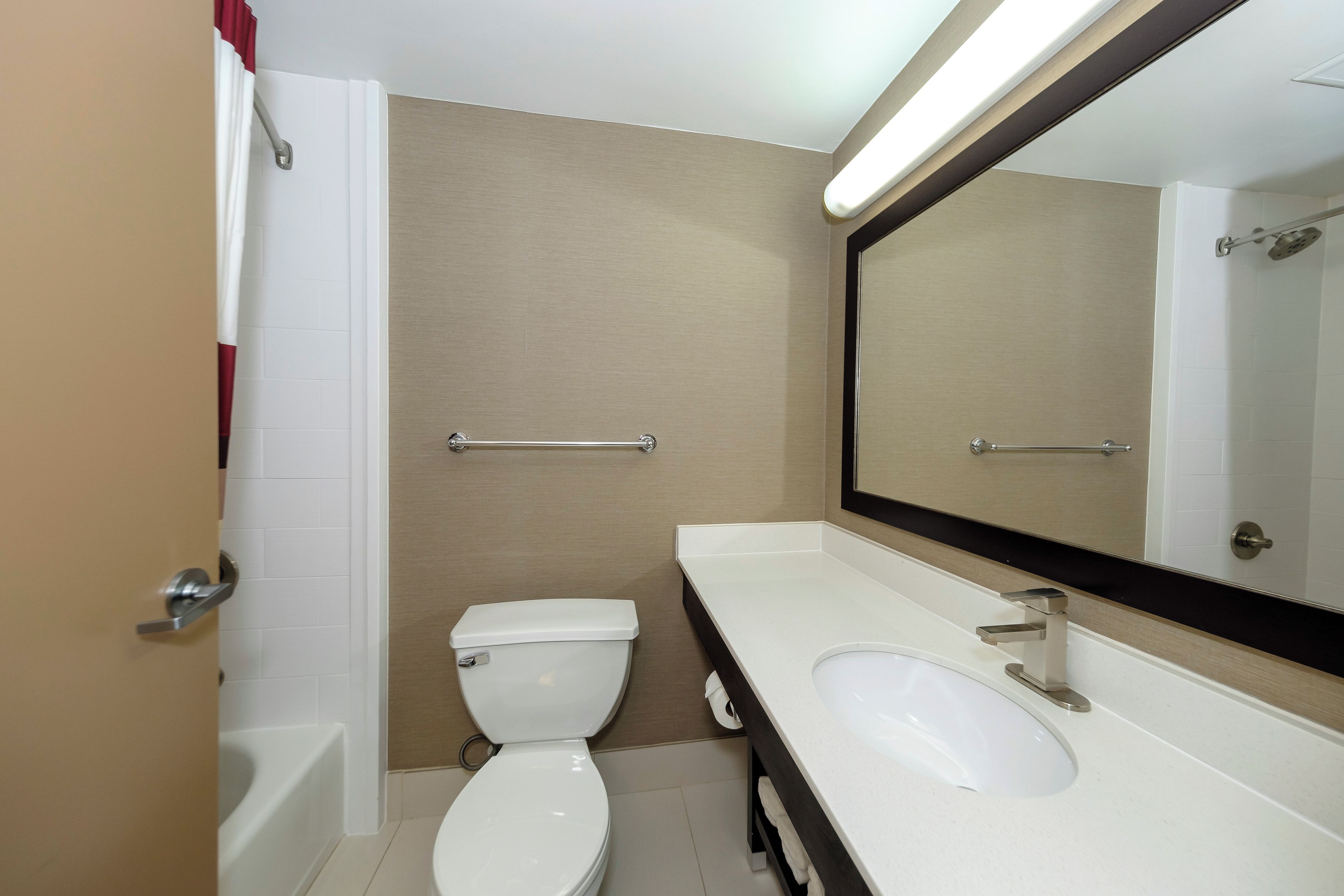 A bathroom with a toilet, sink, and mirror.