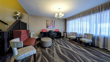 A hotel lobby with a sofa, chairs, a coffee table, a desk, and a chandelier.