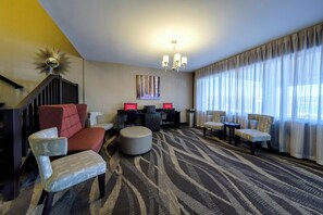 Un hall d’hôtel avec un canapé, des fauteuils, une table basse, un bureau et un lustre.
