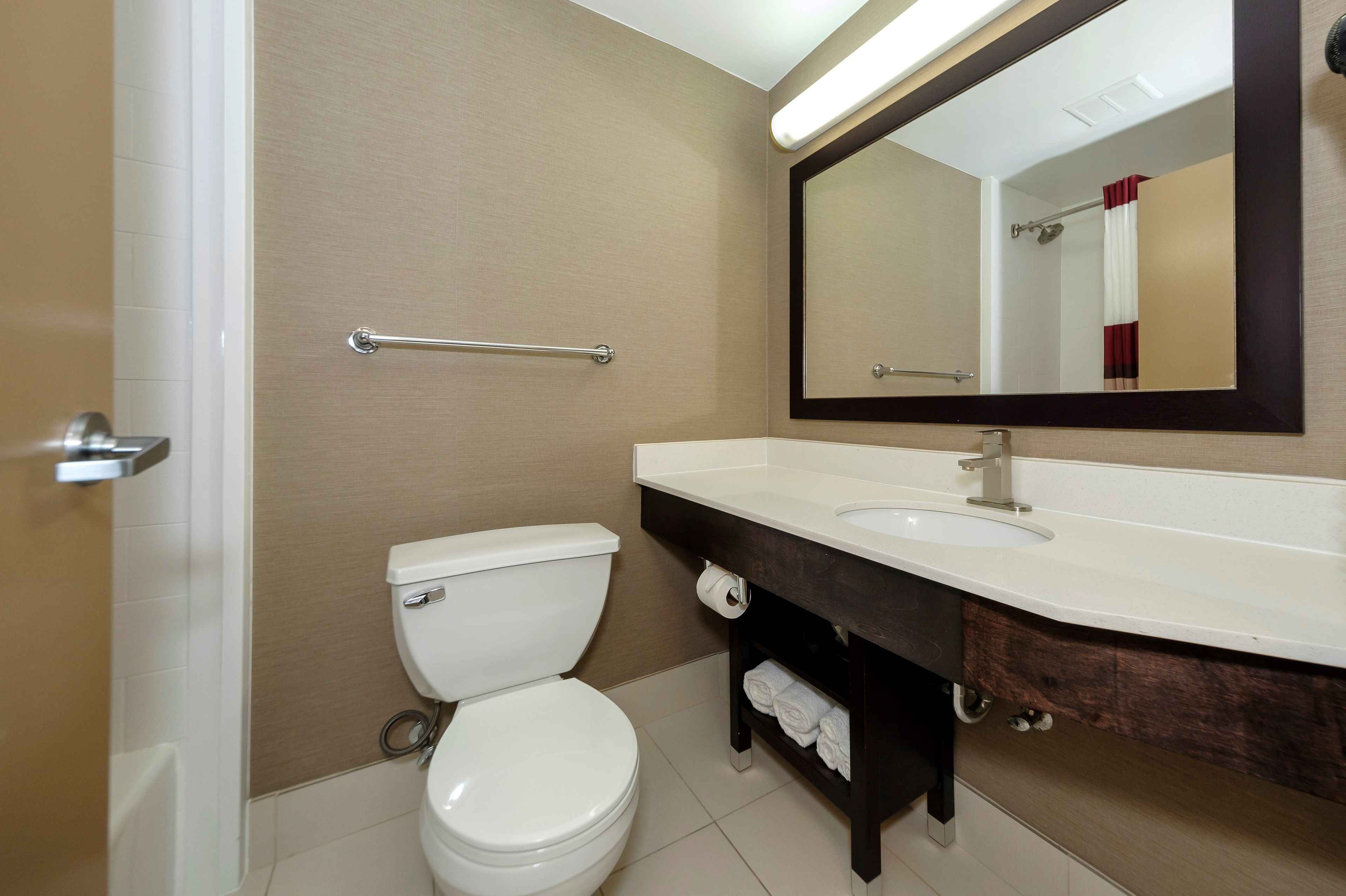 A bathroom with a toilet, sink, and mirror.