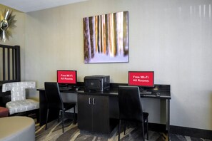 Une chambre d’hôtel équipée d’un bureau, de deux chaises, d’une imprimante et d’un panneau indiquant que le Wi-Fi est gratuit dans toutes les chambres.