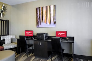 Habitación de hotel con escritorio, dos sillas, una impresora y un cartel que indica Wi-Fi gratuito en todas las habitaciones.