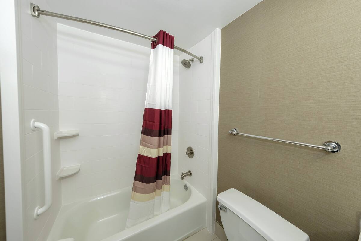 Ein Badezimmer mit einer weißen Wanne, einer Duschvorhang und einer Haltestange.