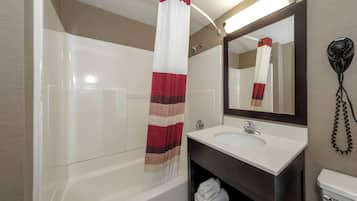 A bathroom with a bathtub, a sink, a mirror, and a hairdryer.