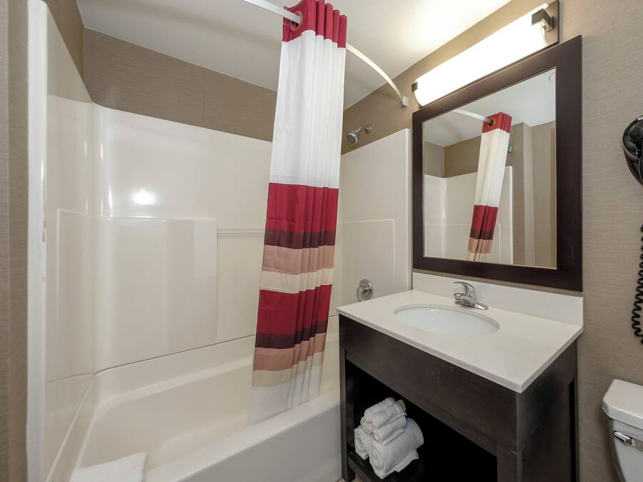 A bathroom with a bathtub, a sink, a mirror, and a hairdryer.
