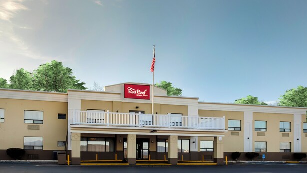 Edificio de Red Roof Inn & Suites de dos pisos, con balcón y bandera estadounidense.