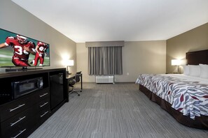 Una habitación de hotel con cama, escritorio, televisor, microondas y aire acondicionado.