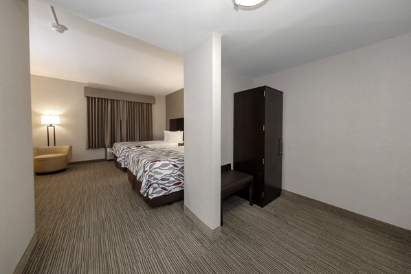 A hotel room with a bed, a chair, a wardrobe, and a desk. - Red Roof Inn & Suites Newburgh – Stewart Airport/ West Point (New Windsor)