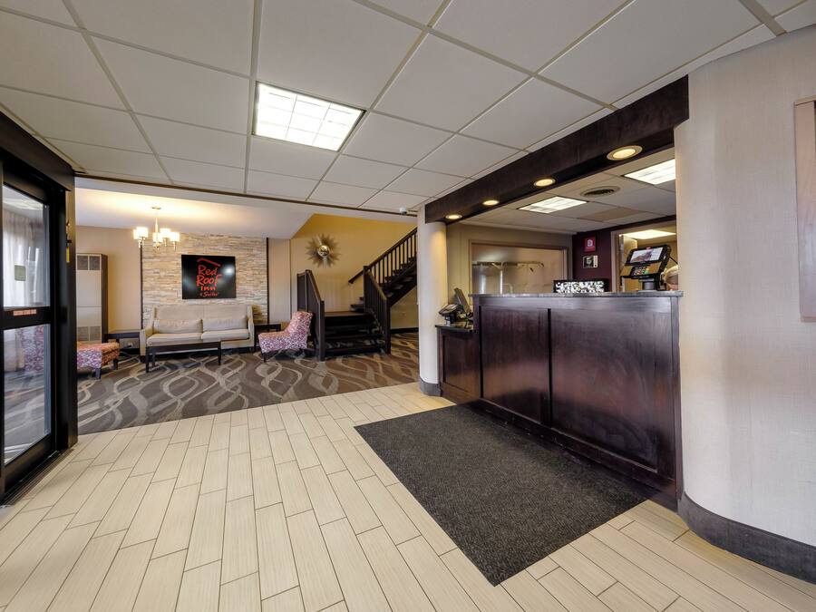Un hall de hotel con una recepción, un sofá, una escalera y una alfombra estampada.