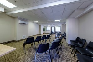 Un salón de conferencias con filas de sillas, una mesa larga y un ventanal amplio.