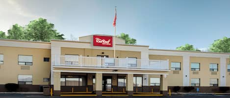 Edificio de Red Roof Inn & Suites de dos pisos, con balcón y bandera estadounidense.