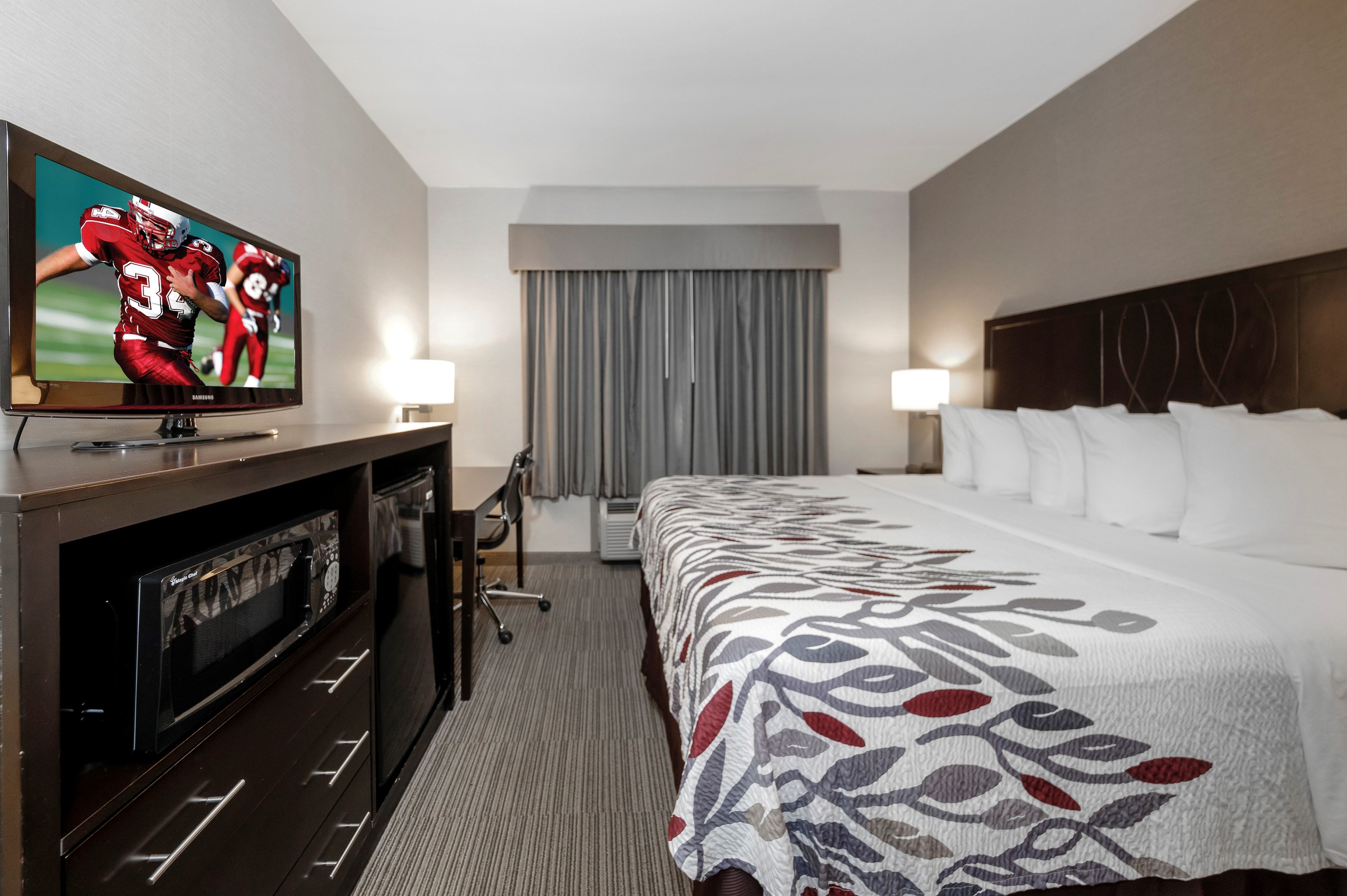 Une chambre d’hôtel avec un lit, une télévision, un bureau et une chaise.