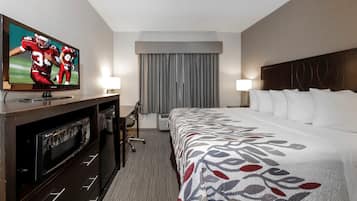 Une chambre d’hôtel avec un lit, une télévision, un bureau et une chaise.