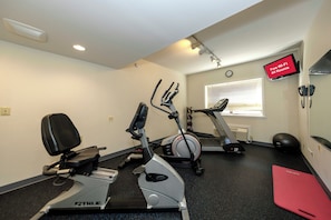 Un gimnasio con bicicletas estáticas, una cinta de correr y pelotas de ejercicio.