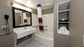 A modern bathroom with a white sink, a large mirror, a towel rack, and a shelf with neatly folded towels.