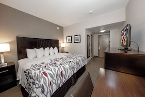 Una habitación de hotel con una cama grande, mesitas de noche, un escritorio y un televisor.