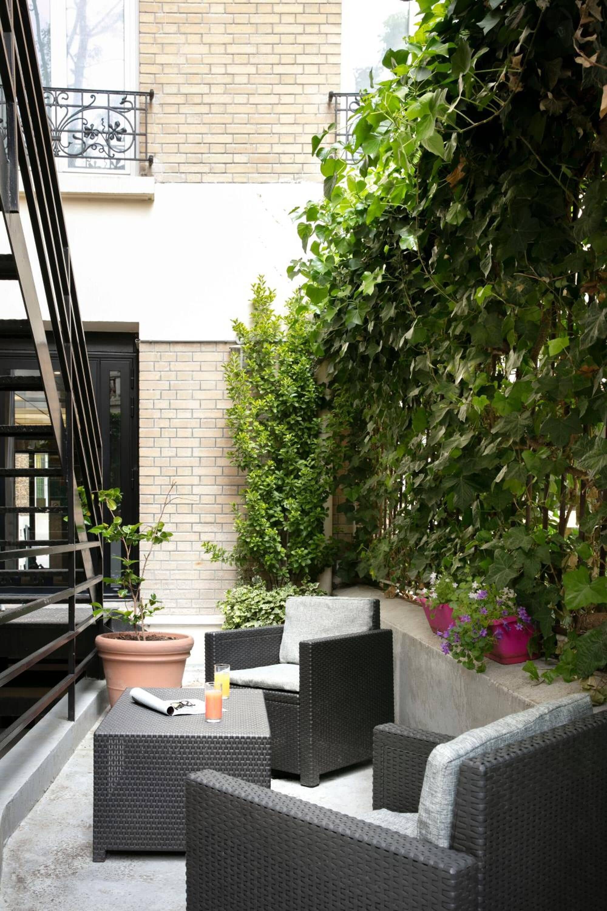 An outdoor seating area with wicker furniture, a potted plant, and a brick wall.