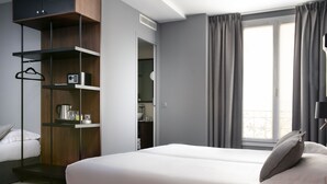 Habitación de hotel moderna con una cama grande, armario empotrado y vistas a la ciudad.