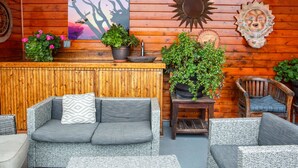 A cozy wooden cabin interior with a sofa, chairs, and potted plants. - Inn at Avila Beach (Avila Beach)
