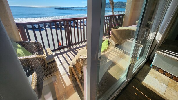 A balcony with wicker furniture, a glass door, and a view of the beach and ocean. - Inn at Avila Beach (Avila Beach)