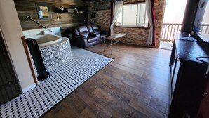 A rustic room with a wooden ceiling, a bathtub, a leather sofa, and a TV. - Inn at Avila Beach (Avila Beach)