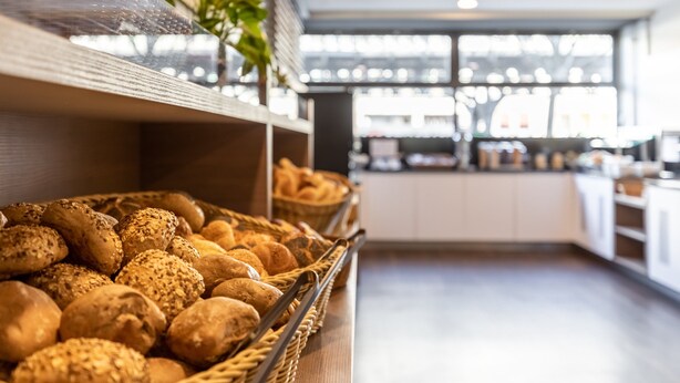 Mostrador de panadería con panes y pasteles variados.