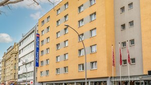 Un hotel de varios pisos, con un llamativo letrero que dice 'Alton Hotel' y varias banderas.
