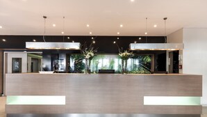 Un mostrador de recepción moderno con diseño minimalista, con acabados de madera clara e iluminación integrada.