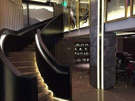 Un interior moderno con una escalera curva, una columna de mármol y una exhibición de jarrones.