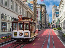 Um teleférico numa linha vermelha em uma cidade com edifícios históricos e um mural na parede.