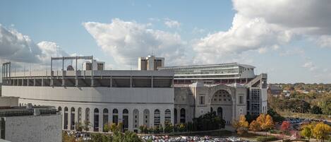 A large, modern building with a curved facade and multiple levels, surrounded by trees and a parking lot.