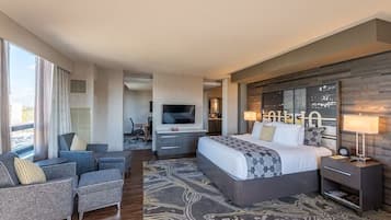 A modern hotel room with a large bed, a TV, a desk, and a sofa.