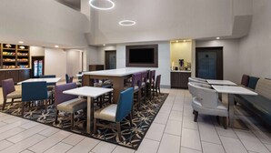 A modern hotel lobby with a bar area, seating arrangements, and a television screen. - La Quinta Inn & Suites by Wyndham North Orem (Orem)
